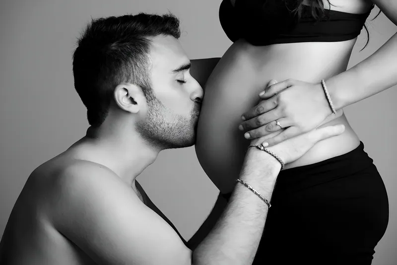 Gravidanza di coppia in bianco e nero, bacio sul pancione